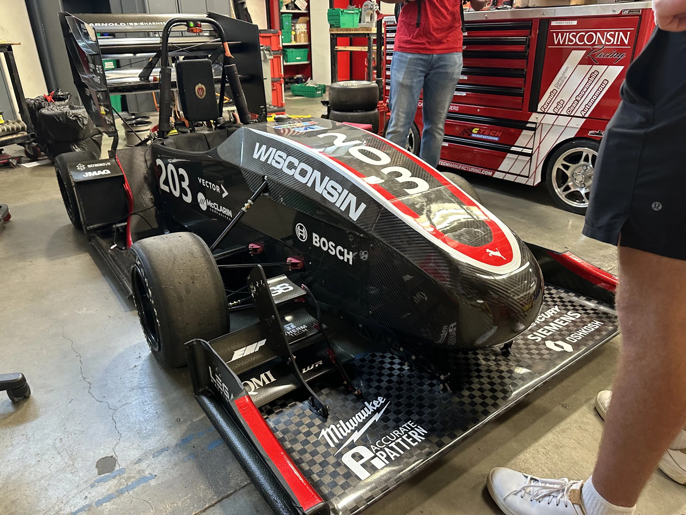 Wisconsin Racing Formula SAE car number 203 in the workshop, showing its front wing, suspension, and cockpit.